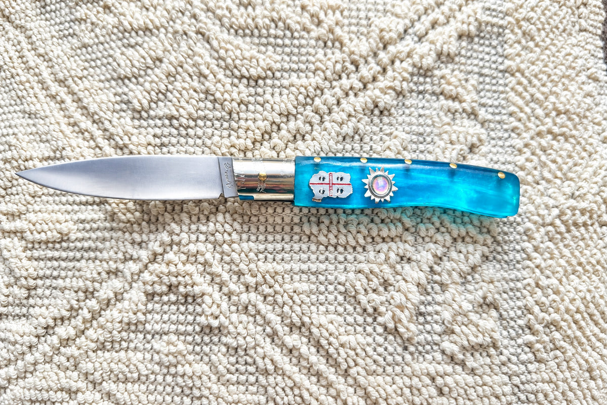 Coltello  pattadese con anima  , lama liscia 10,5CM  impugnatura in resina colore oceano,con la Sardegna e il sole incastonati.